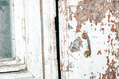Rusty handle of old door with cracked paint . Abandoned place