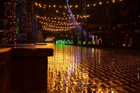 Rainy Christmas night . Street decorations and garlands with wet pavementの写真素材
