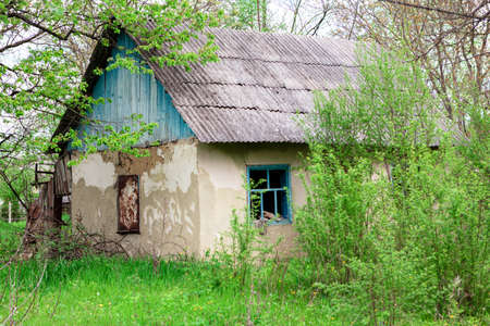Overgrown abandoned house in a country . Abandoned house with a slate roofの写真素材
