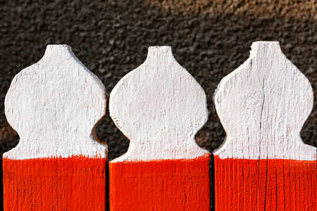 Picket fence in candle form . Top part of wooden fence . Planks painted in red and whiteの写真素材