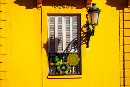 Window with shutters on the yellow wall. Street light on the house wall. Window with decoration in traditional Spanish styleの写真素材