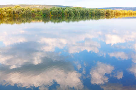Riverside trees and clouds reflection in the water . Danube river in the autumnの写真素材