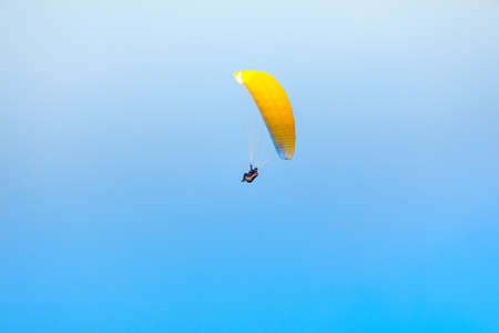 Paragliding at the blue sky . Flying Paraglider extreme sport . Yellow parachuteの写真素材