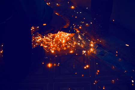 Sparks on the black background . Work with a grinder . Spark particles in the dark room . Cutting metalの写真素材