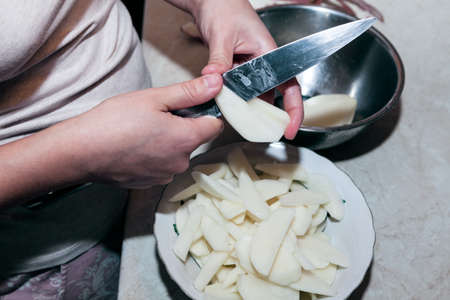 Cutting potato chips . Knife in hands for cutting potatoes . Home kitchen sceneの写真素材
