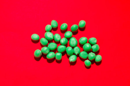Green peas at red background . Peas rich in fiber and proteinの写真素材