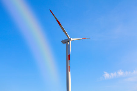 Windmill with rainbow . Wind generator against blue skyの写真素材