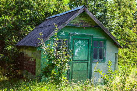 Barn in the forest . Wooden hut in the woodland . Rustic house colored in greenの写真素材