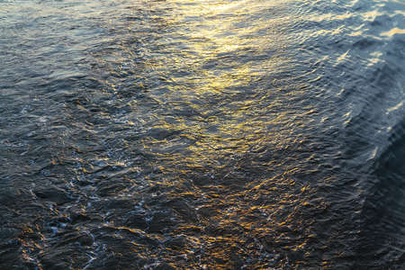 Glittering water background . Ripples with sunlight . Twilight reflection in the sea