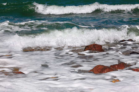 Sea waves with foam beating the rocks