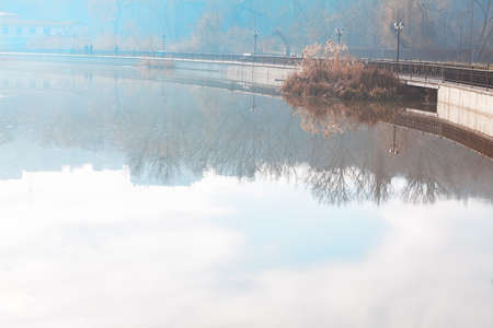 City lake in the autumn . Urban park with nature reflection in water