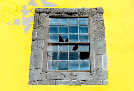 Yellow wall and window with broken glassの写真素材