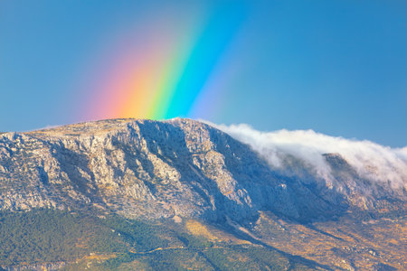 Beautiful rainbow over the mountain . Scenic view of rainbow and clouds over the mountainsの写真素材
