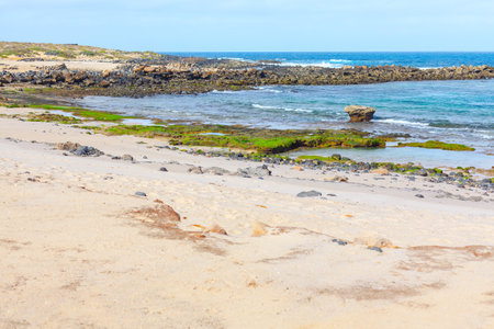 Island coast with sandy rocks on sandy beach