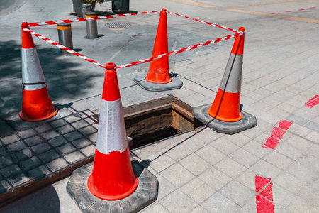 Street sinkhole repair . Red repair cones fencing the streetの写真素材