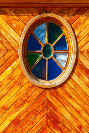 Round window at wooden wall . Window with colorful glassの写真素材