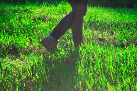 Legs of a young woman walking on a green meadow.の写真素材