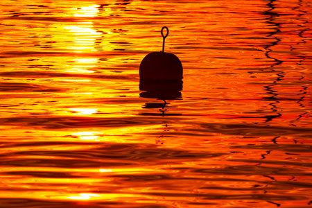 Silhouette of fishing float floating in the sea at sunset.