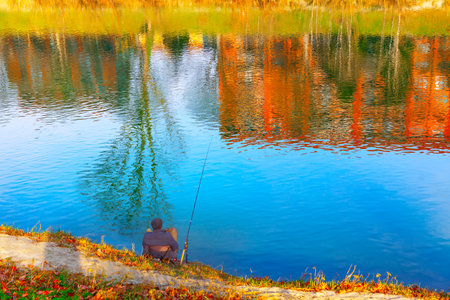 Fisherman on the shore of the lake at autumn dayの写真素材