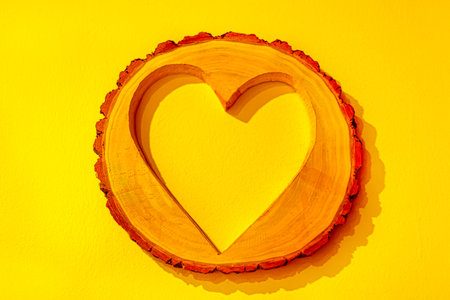 Heart shape made of wood on yellow background, valentine conceptの写真素材