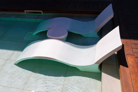 Swimming pool with sun loungers on the edge of the pool