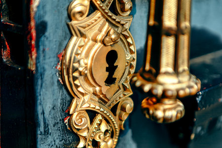 Wooden door with a shiny gold door knob and handle. Gold key with a keyhole is shown. Concept of...