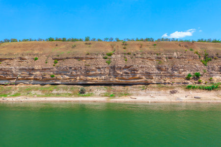 Rocky shoreline with a body of water in the foreground. River beside a towering cliff, creating a serene coastal sceneの写真素材