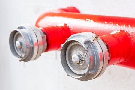 Red fire department connection FDC with two caps attached to the outlets. Protection system, which allows firefighters to quickly connect hoses to the water supply in case of a fire emergencyの写真素材