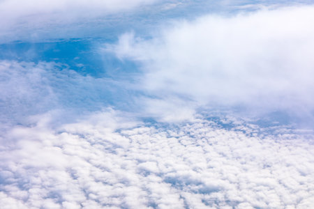 Aerial view of soft white clouds seen from an airplane window. Experience the breathtaking beauty of...