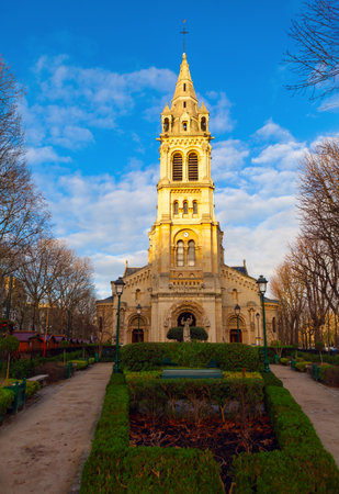 Picturesque church with a tall, ornate bell tower, surrounded by a well-maintained garden and pathways, under a clear blue sky. Eglise Saint-Pierre de Neuilly-sur-Seine in Parisの写真素材
