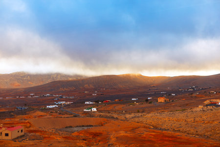 Rugged and arid landscape of Fuerteventura, with scattered houses and buildings dotting the terrain....
