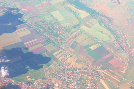Aerial view of rural landscape showcases patchwork fields, winding roads, and scattered villages....