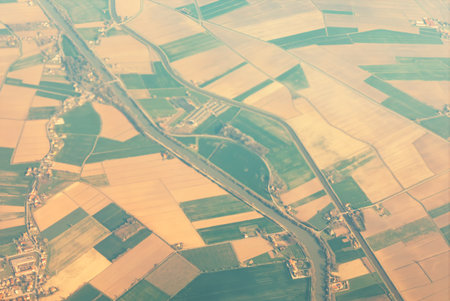 Patchwork of agricultural fields divided into rectangular plots of varying shades of green and...