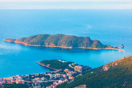 Scenic view of Becici on Budva Riviera, with a coastal town nestled at the base of green hills, overlooking calm blue waters of Adriatic Sea. In distance the lush Sveti Nikola Island rises from seaの写真素材