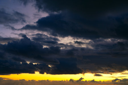 Dramatic sky with dark storm clouds blocking light from rising sun. Scene highlights the raw power of nature, with interplay of light and shadow adding depth and intensity to atmosphereの写真素材