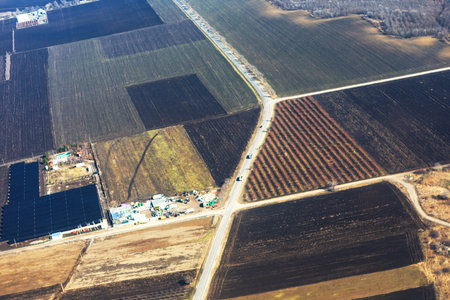 Aerial view of geometric agricultural fields with varied earthy tones, intersected by angular roads...