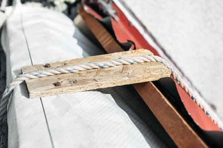 Rooftop repair in progress, with a wooden plank and rope used to secure materials or provide support...
