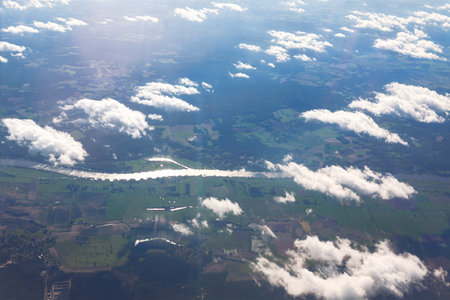 Clouds drift across a landscape of varied terrain, showcasing a river path from above. River...