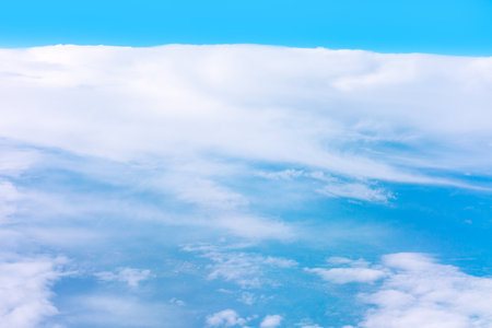 Clouds view from above with a bright blue sky on top. Vast expanse of white, fluffy clouds fills the...