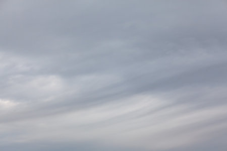 Wispy clouds drift across a muted sky. Dense layer of gray and white clouds fills the sky. Clouds...