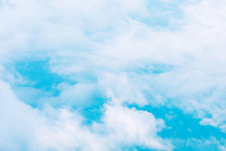 Blue sky filled with soft, white clouds, creating a serene and expansive atmosphere. Clouds are...