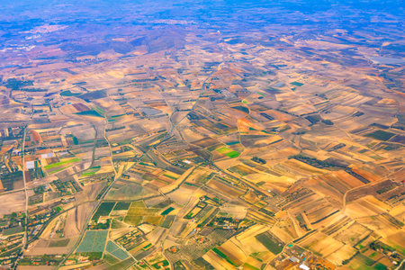Aerial photo shows a patchwork of agricultural fields found in Spain. The landscape is a mosaic of different colored crops and barren landの写真素材