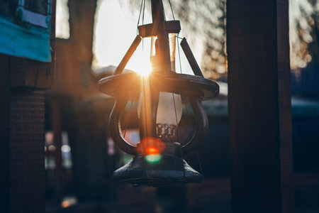 Hanging lantern silhouetted against bright, setting sun flare. Decorative lantern captured during golden hourの写真素材