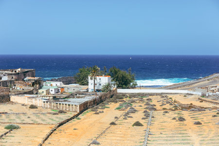 Small whitewashed houses sit between an arid, volcanic landscape and the deep blue Atlantic in gran...