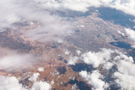 Desert terrain partly veiled by scattered clouds. Valleys and ridges with dynamic cloud cover above