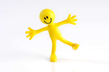 A smiling yellow figure balancing on one leg arms outstreached on a white background