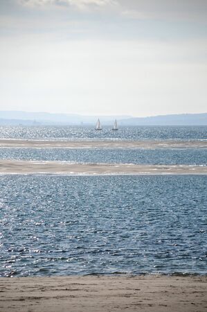 To sailing boats in the distance with in the foreground sandbanks and in the far distance landの写真素材