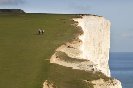 Seen from the rear  and at a far distance two walkers on the South Downs coastal cliff path in...