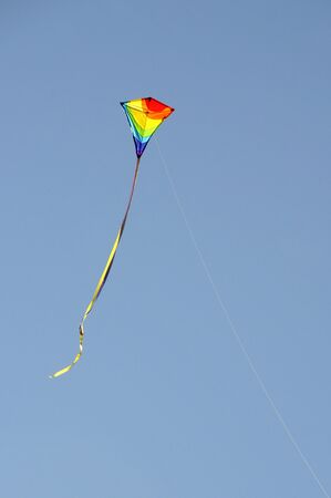 a small childs colourful kite and line against a blue skyの写真素材