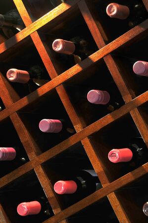 A wall mounted wine rack in cellar, with necks of assorted bottlles of red wine showingの写真素材